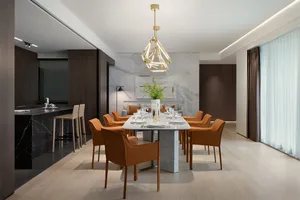 A modern dining room featuring a marble table surrounded by orange chairs and a geometric chandelier.