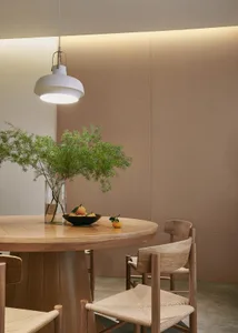 A modern dining room featuring wooden furniture with a round table and chairs, illuminated by a pendant light and enhanced wi