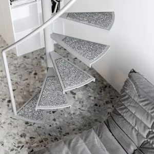A modern grey staircase features a white metal railing on a terrazzo floor.