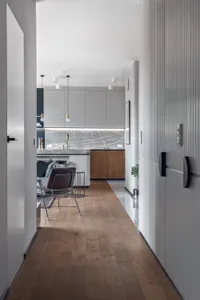 Modern kitchen interior with light wood floors, grey stone countertops, and minimalist furniture.