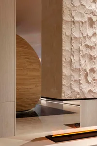 A modern living room with a bamboo ball sculpture and stone walls.