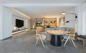 Modern living room with concrete furniture, including a round table with a black base and wooden chairs, a comfortable couch,