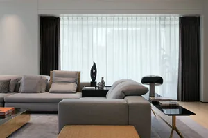 Modern living room with fabric sofa, glass tables, and abstract sculptures.