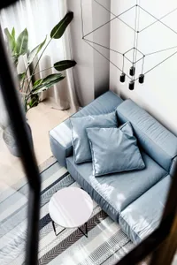Modern living room with a comfortable gray sofa, decorative coffee table, geometric light fixture, and striped rug, featuring