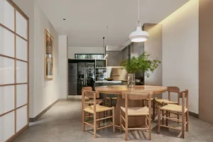 Modern residential kitchen with a round wooden dining table and chairs, a sleek refrigerator, and a green plant centerpiece.
