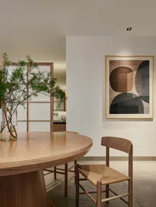 A modern dining room with a wooden table, chairs, and a plant in a vase.
