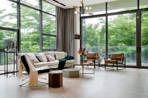A modern living room featuring wood flooring, leather chairs, and a glass coffee table.