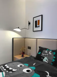 Modern minimalist bedroom with a bed featuring a dinosaur-themed quilt and a dinosaur-themed pillow, a nightstand with a Tran
