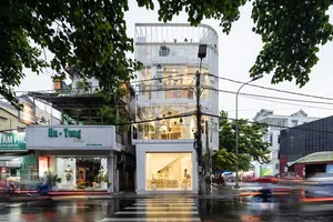 Street scene featuring a modern building with glass walls, concrete façade, and metal structures.