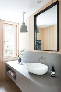 Modern minimalist bathroom featuring concrete countertop, floating sink, and wooden paneling on the walls.