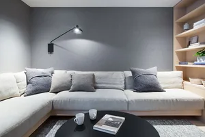 A cozy minimalist living room with a comfortable couch, pillows, and a coffee table.