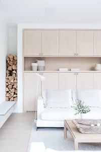 A minimalist living room featuring a white sofa, wooden coffee table, and a floor lamp with a white shade.
