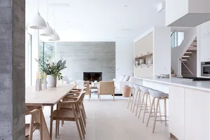 A modern minimalist residential interior featuring light wood finishes, white marble countertops, and concrete accents.