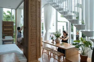 A modern apartment featuring woven fiber blinds, wooden stools, and a white bed.