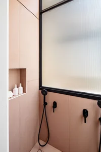 Modern bathroom shower area with pink ceramic tiles and black hardware.