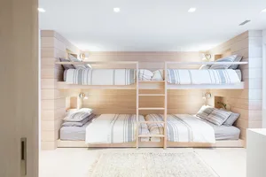 Modern bedroom featuring wooden paneled bunk beds with striped bedding and wall-mounted lights.