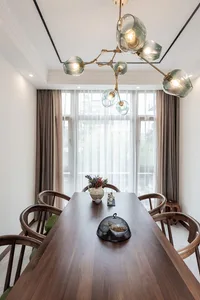 A modern dining room with a wooden table, green cushions, and a chandelier.