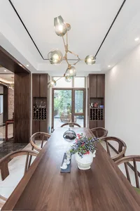 Modern dining room featuring wooden furniture, glass chandelier, and a view of an outdoor patio.