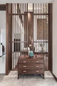 Modern entrance foyer with wooden slat partition, marble floor tiles, and decorative wooden chest with vase and dried plants.