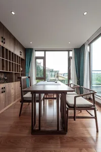 A modern dining room featuring a wooden table and chairs, with a large window and green curtains.