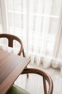 A modern interior featuring wooden furniture and curtains near a window.