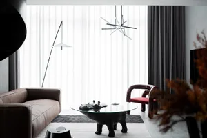 Modern living room featuring glass coffee table, metal pendant light, and leather sofa.