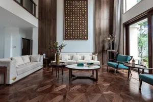 Modern living room with white sofas, blue armchairs, and a coffee table on wooden flooring.