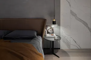 A modern bedroom featuring a marble wall and a bed with a brown leather headboard.