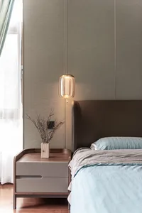 Modern minimalist bedroom with light blue bedding, wooden nightstand, and green foliage on the nightstand.