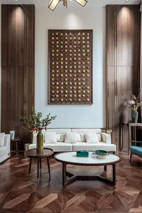 A modern white sofa with two round marble tables and plants on side tables in a room with wooden walls and floor.