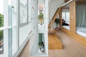 A modern, white-designed indoor space featuring wooden furniture and flooring, a white screen divider, and a potted plant.