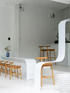 A modern and minimalist coffee shop with wooden stools and white surroundings.
