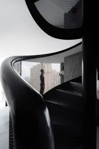 Black metal spiral staircase with a perforated metal railing.