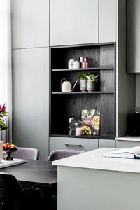 A modern kitchen with grey cabinets and concrete countertops featuring decorative items.