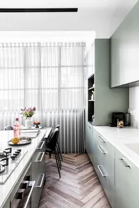A modern kitchen with minimalist design, featuring marble countertops and herringbone wood flooring.