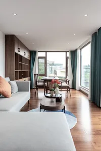 Modern living room furniture with wooden accents and glass walls, featuring a comfortable seating area and a dining table.