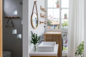 Modern bathroom featuring a white vessel sink, wooden shelves, and white shelves with glass block window
