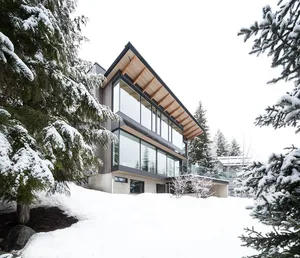 A modern lodge with wood and glass construction amidst a snowy landscape.