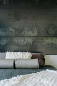 Modern bedroom interior featuring a concrete headboard and plush fur throw blankets on a bed.