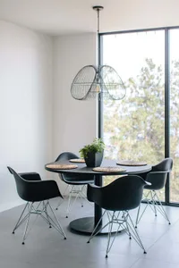 Modern dining room featuring black chairs, a black round table, and a metallic wire pendant light