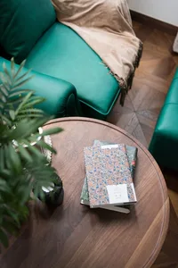 A modern green sofa with a beige throw blanket in a living room setting.