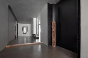 A modern interior space with concrete walls and a wooden sculpture
