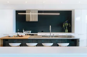 A modern kitchen featuring granite countertops, white cabinets, and stainless steel appliances.