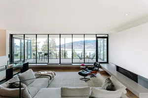 Modern minimalist living room with floor-to-ceiling glass walls and a sleek concrete fireplace, featuring contemporary furnit