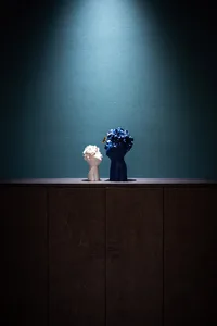 A blue ceramic vase with floral decoration sitting on top of a dark wooden cabinet.