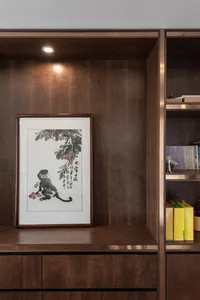 A wooden bookshelf with a framed painting of a monkey and flowers on it.
