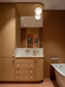 A minimalist bathroom featuring wooden cabinets and a white sink.