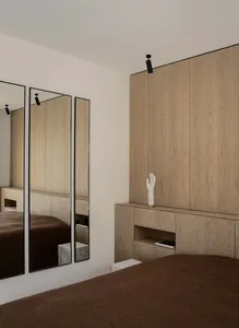Minimalist bedroom featuring wooden vanity and mirrors.