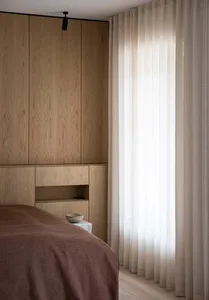 Minimalist bedroom featuring wooden cabinets and curtains