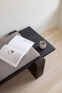 A minimalist interior with a black wooden coffee table, an open book, and a ceramic cup.